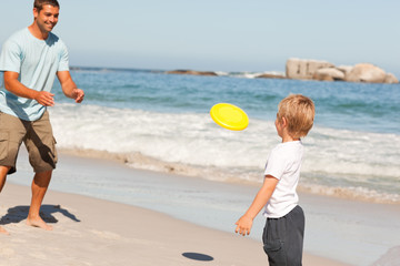 Little boy playing frisbee with his father