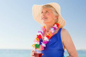 Elderly woman drinking a cocktail on the beach