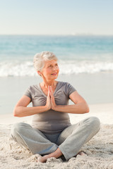 Fototapeta na wymiar Senior woman practicing yoga on the beach