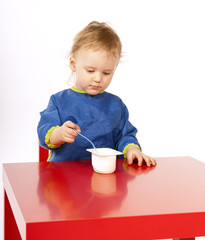 Little baby is eating on red table
