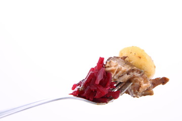 Piece of a pork steak, a dumpling and beet salad on a fork