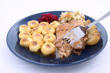 Pork steak and dumplings being eaten with a fork
