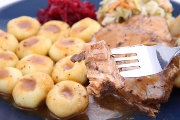 Pork steak and dumplings being eaten with a fork