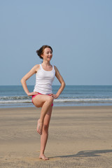 Young woman doing exercises on the beach