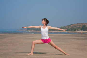 Young woman doing yoga on the beach