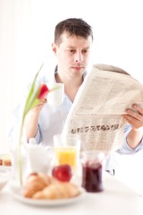man reading the newspaper and having breakfast