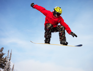 Snowboarder jumping through air with  blue sky in background