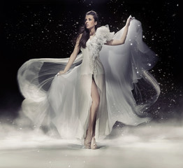 Sensual brunette woman dancing in white dress