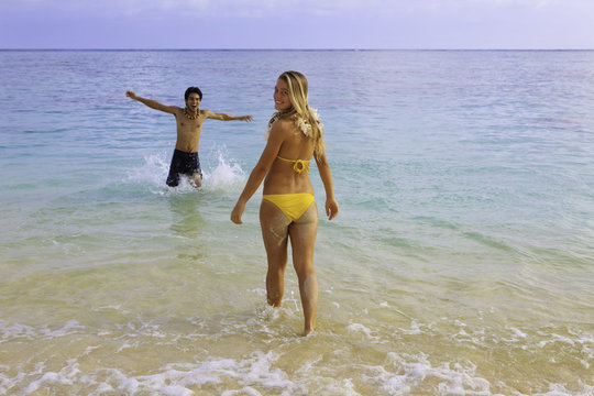 young couple frollicking at the beach in hawaii