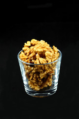 Walnut kernels in a cup on black background