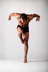 young male dancer posing over grey background