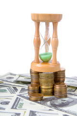 Hourglass on  a pile of coins on white background