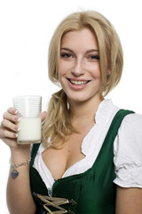 Mädchen im Dirndl hält ein Glas Milch in der Hand