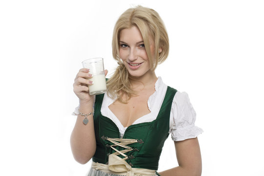 Mädchen im Dirndl hält ein Glas Milch in der Hand