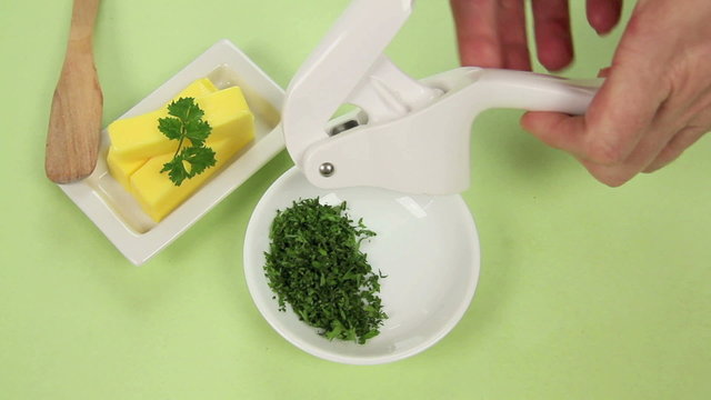 Preparing garlic butter by mixing herbs and garlic with butter