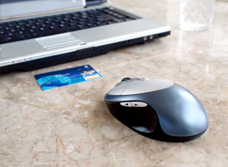Credit card, laptop and computer mouse on the table