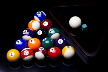Billiard balls, cue on black table