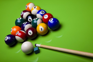 Billiard balls, cue on green table