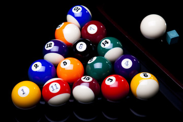 Billiard balls, cue on black table