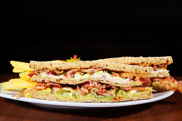 Toast Sandwich mit Speck, Käse, Salat und Pommes closeup
