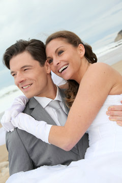 Groom holding bride in his arms at the beach