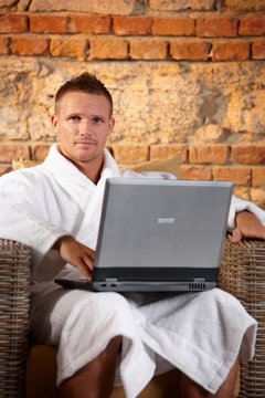 Handsome man in bathrobe with computer