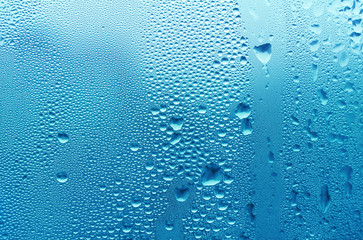 Bright blue water drop on glass, natural texture