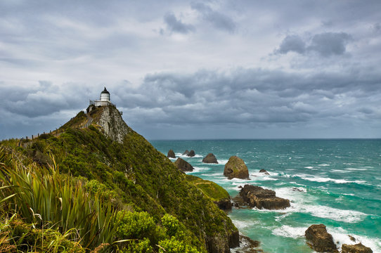 Nugget Point Light House and dark clouds in the sky