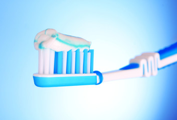 brush for toothpaste at in the girl's hand on blue background