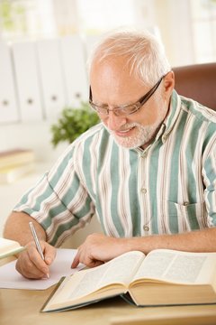 White hair pensioner writing letter at home