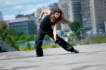 Beautiful girl dancing hip-hop over urban landscape