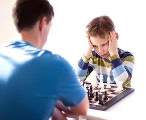 boy playing chess with his father