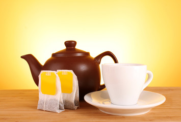 Close-up of tea bag and teapot on yellow background
