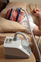 Man with sleep apnea using a CPAP machine in bed.