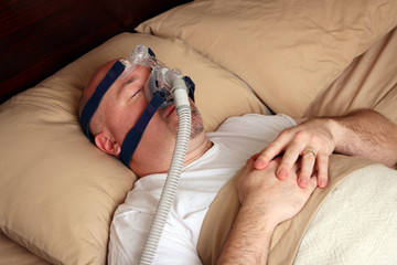 Man with sleep apnea using a CPAP machine in bed.
