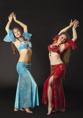 Two woman dance and smile in arabian costume