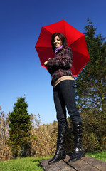 Young woman standing outdoor with red umbrella