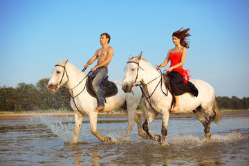 Fototapeta na wymiar Man and a woman in love with the sea on horseback