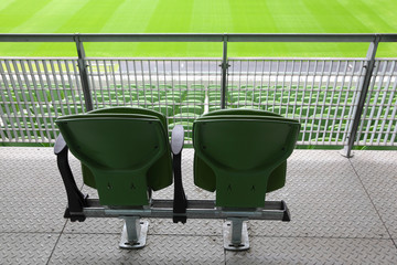 Naklejka premium Two green plastic seats on tribune of large stadium