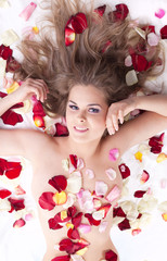Young beauty nude woman lay in rose petals
