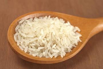Raw rice grains on a wooden spoon