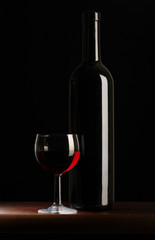 Bottiglia di vino rosso con bicchiere su fondo rosso
