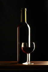 Bottiglia di vino rosso con bicchiere su fondo nero