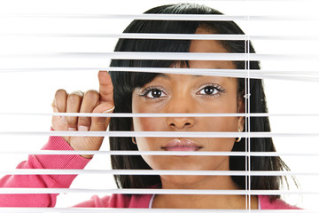 Woman looking through venetian blinds