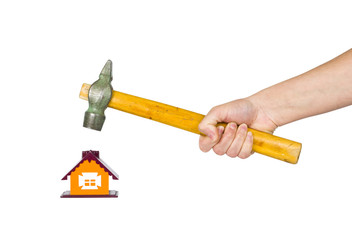 hand with a hammer destroys small house