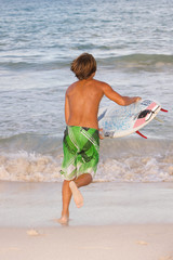 Surfer boy runs toward the ocean