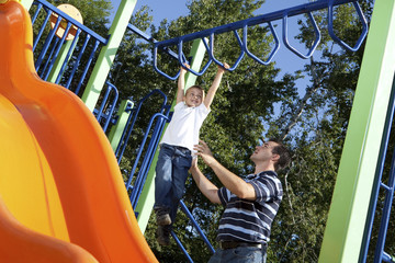 Father and son playing on monkey bars at the park
