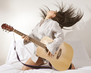 girl is feeling free and playing guitar in a room