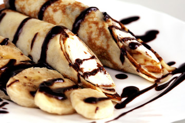 portion of pancakes with stuffing, bananas and chocolate