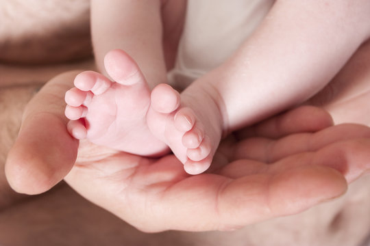 new born baby childs feet in fathers hands